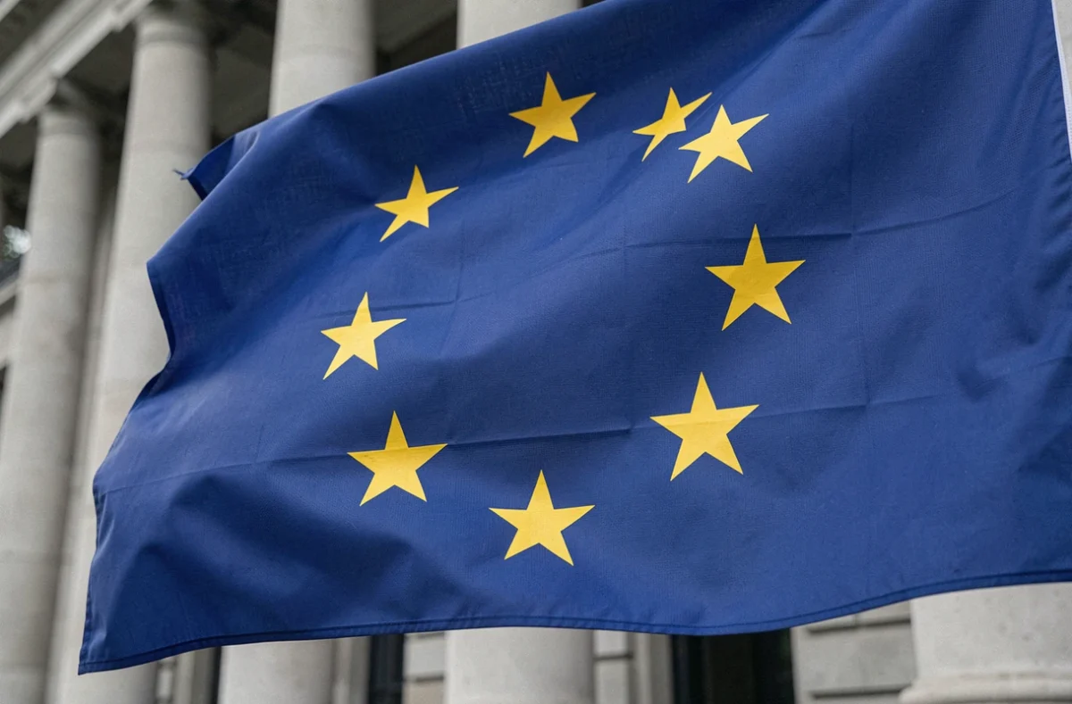 Gros plan sur les douze étoiles dorées du drapeau européen en cercle sur fond bleu cobalt, devant un bâtiment officiel